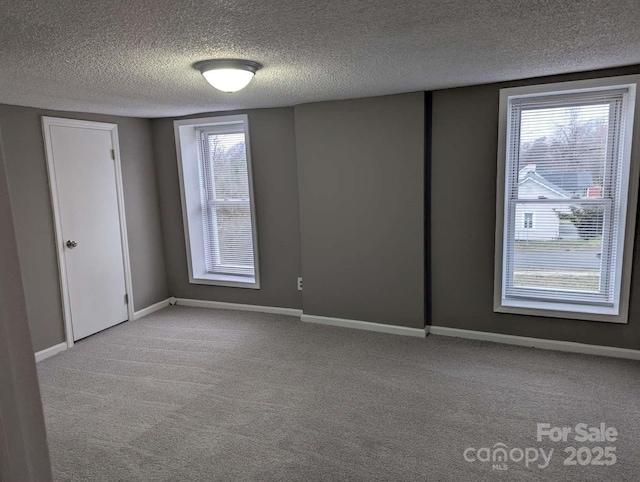 spare room with baseboards, carpet floors, and a textured ceiling