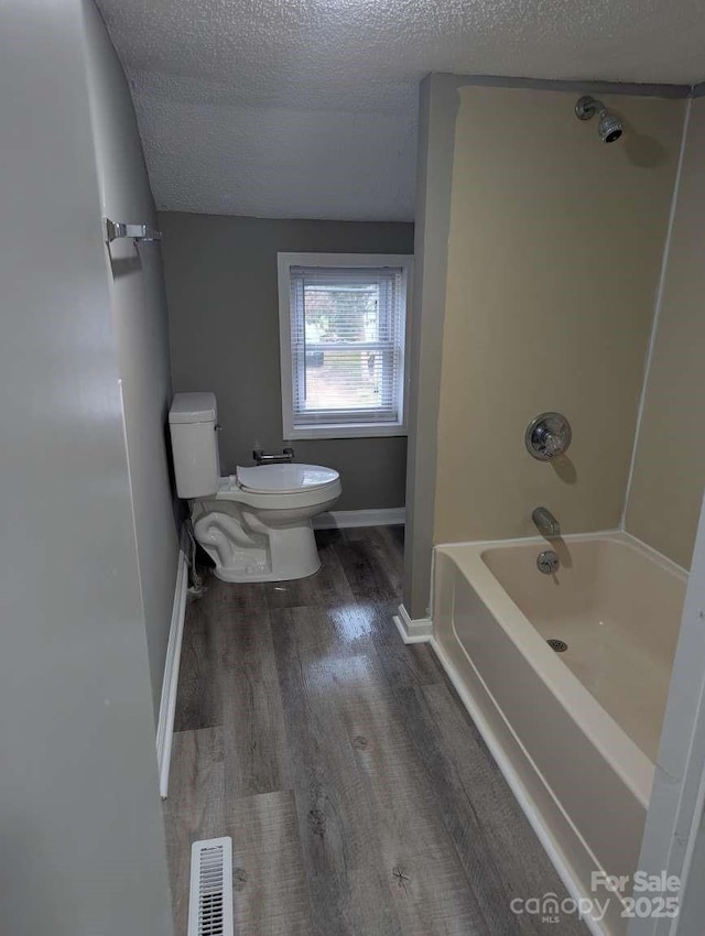 bathroom with visible vents, toilet, shower / tub combination, wood finished floors, and a textured ceiling