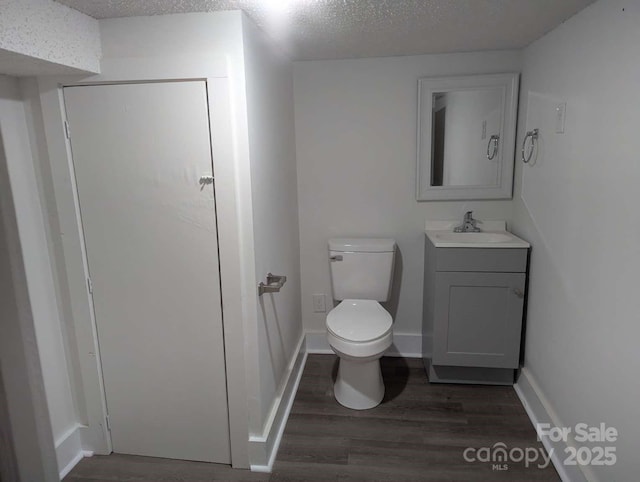 bathroom featuring toilet, wood finished floors, vanity, and a textured ceiling