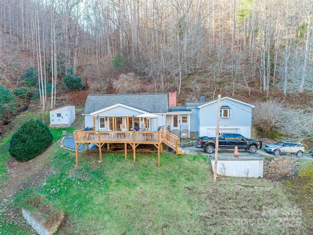 rear view of house with a shingled roof, a wooden deck, a yard, and a chimney