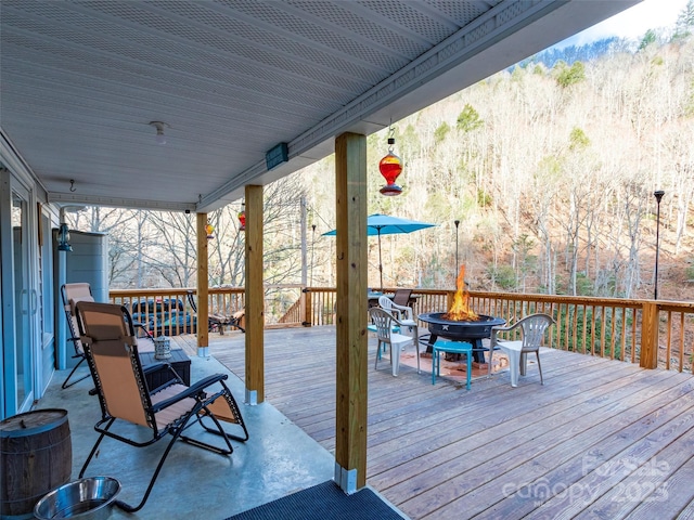 wooden deck featuring a wooded view and an outdoor fire pit