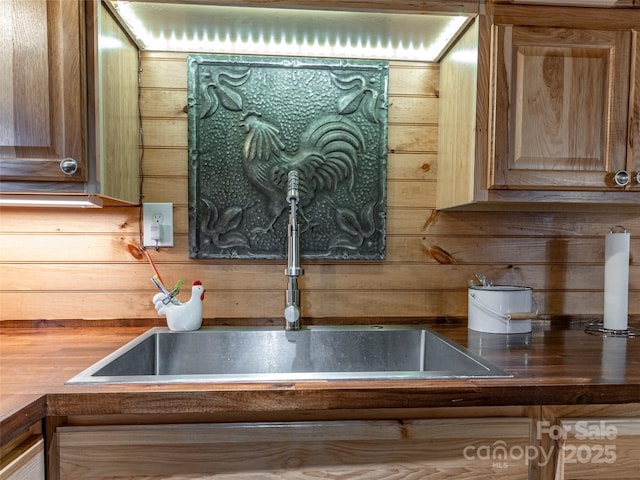 interior details with butcher block counters, wooden walls, and a sink