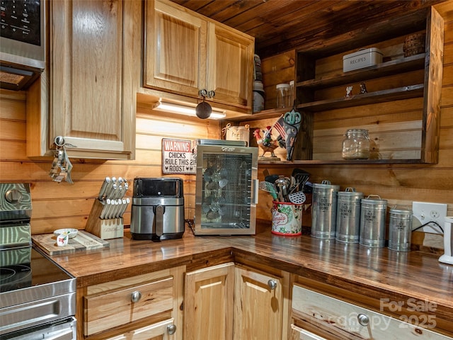 kitchen featuring wooden walls, light brown cabinetry, butcher block countertops, wood ceiling, and stainless steel appliances