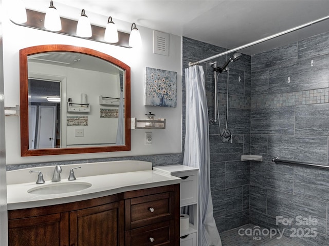 bathroom featuring vanity, visible vents, and tiled shower