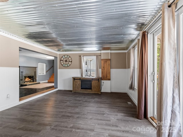 unfurnished living room with stairway, wood finished floors, wainscoting, and a fireplace