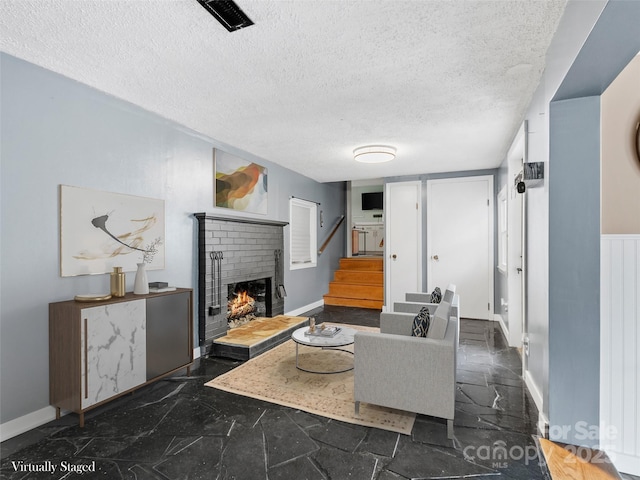 living room with stairway, visible vents, a fireplace, a textured ceiling, and marble finish floor