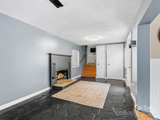 entryway featuring visible vents, a textured ceiling, stairway, a fireplace, and baseboards