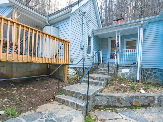 view of side of home featuring crawl space, covered porch, and a chimney