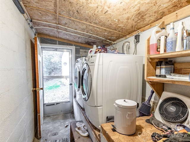 clothes washing area featuring ac unit, concrete block wall, laundry area, and washing machine and clothes dryer