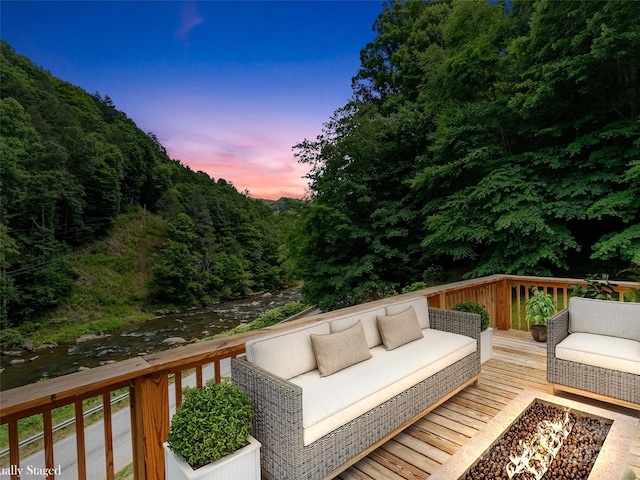 wooden deck with an outdoor hangout area, a view of trees, and a water view