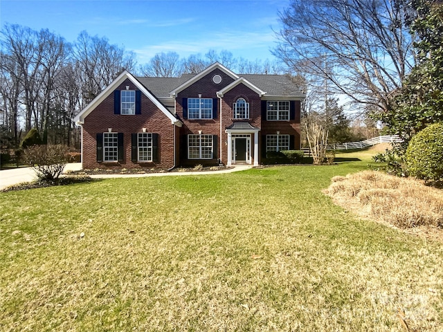 view of front of property with brick siding, a front lawn, and fence