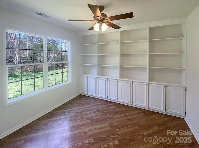 interior space with a wealth of natural light, visible vents, a ceiling fan, and dark wood-style flooring