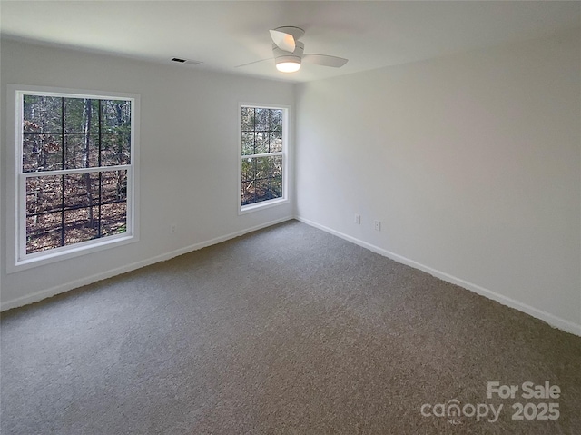 empty room featuring a ceiling fan, baseboards, visible vents, and dark carpet