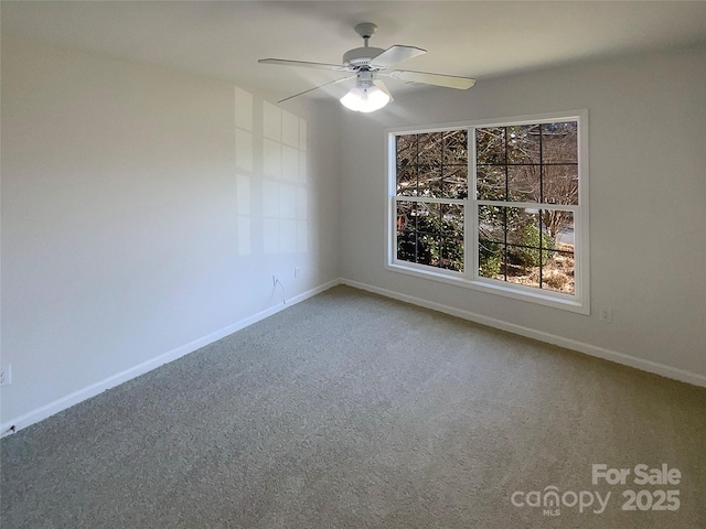 carpeted spare room with a ceiling fan and baseboards