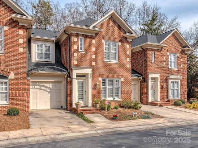 traditional home featuring brick siding, concrete driveway, a shingled roof, and a garage