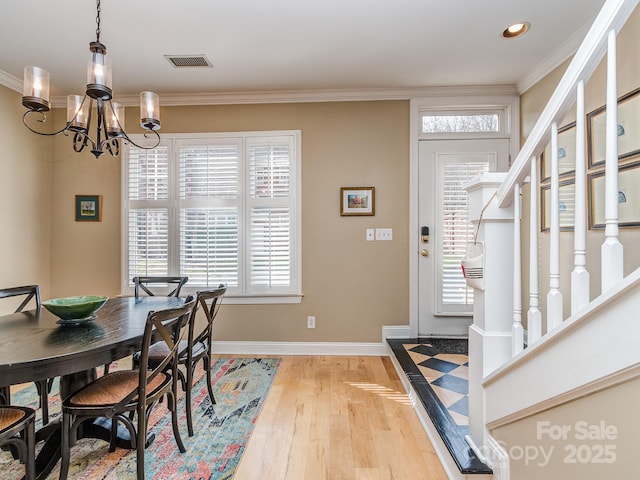 dining space with an inviting chandelier, wood finished floors, crown molding, and visible vents
