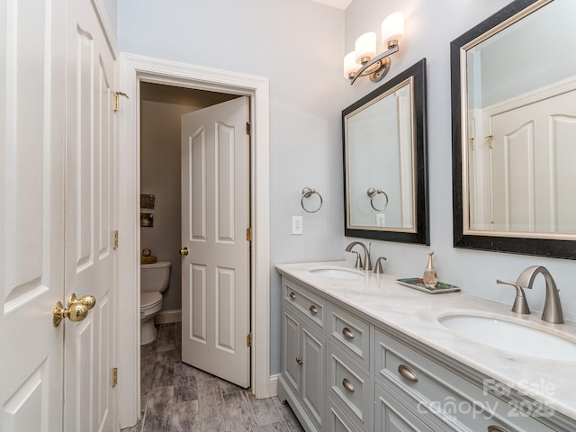 bathroom with toilet, a sink, and double vanity
