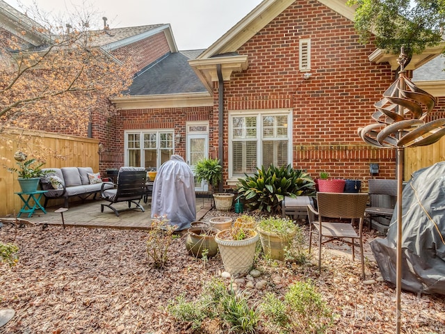 rear view of property featuring brick siding, an outdoor living space, and a patio area