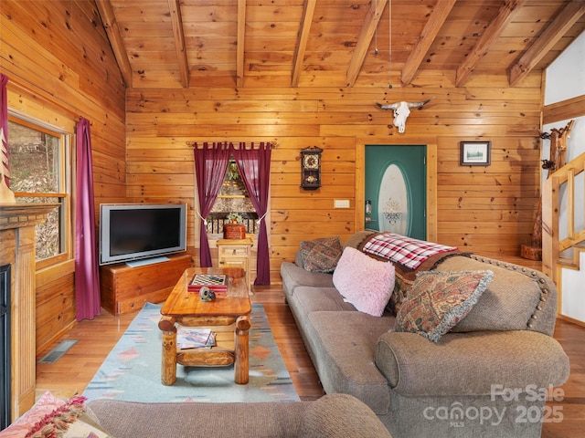 living room with visible vents, light wood-style flooring, wood ceiling, and wood walls