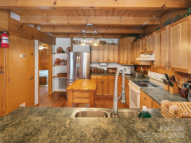 kitchen with under cabinet range hood, beam ceiling, white appliances, and a sink