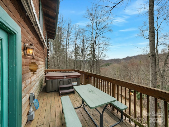 wooden terrace featuring a view of trees and a hot tub