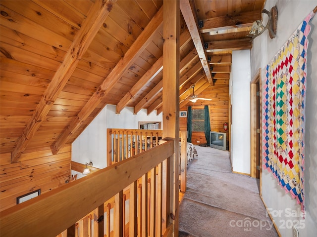 hallway featuring carpet, wood ceiling, vaulted ceiling with beams, and wooden walls