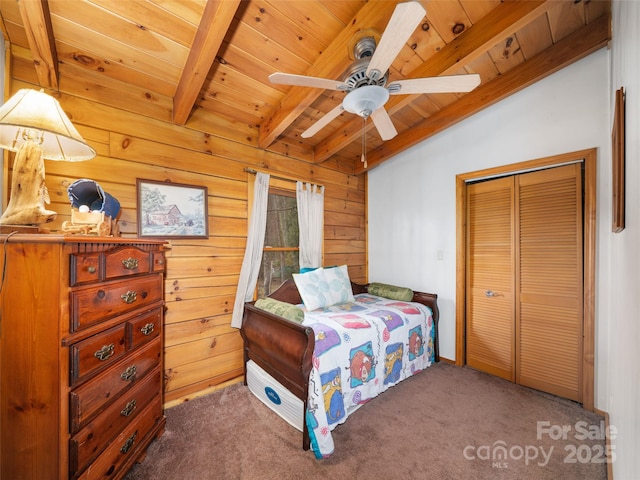 carpeted bedroom with vaulted ceiling with beams, ceiling fan, wood walls, wooden ceiling, and a closet