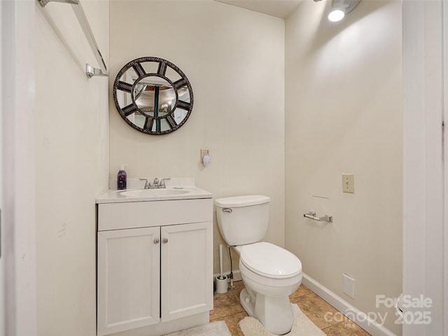 half bath featuring toilet, vanity, and baseboards