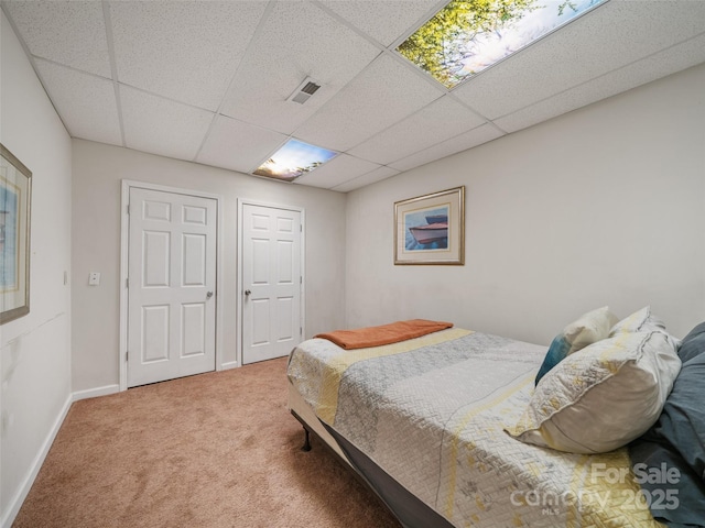 bedroom with a paneled ceiling, visible vents, carpet floors, and baseboards