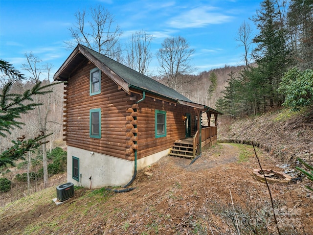 view of property exterior featuring log exterior and central AC unit