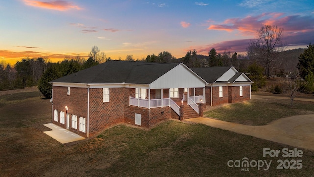 single story home with brick siding, an attached garage, a porch, and a front yard