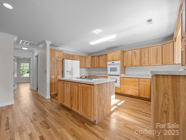 kitchen with white appliances, light countertops, visible vents, and ornamental molding