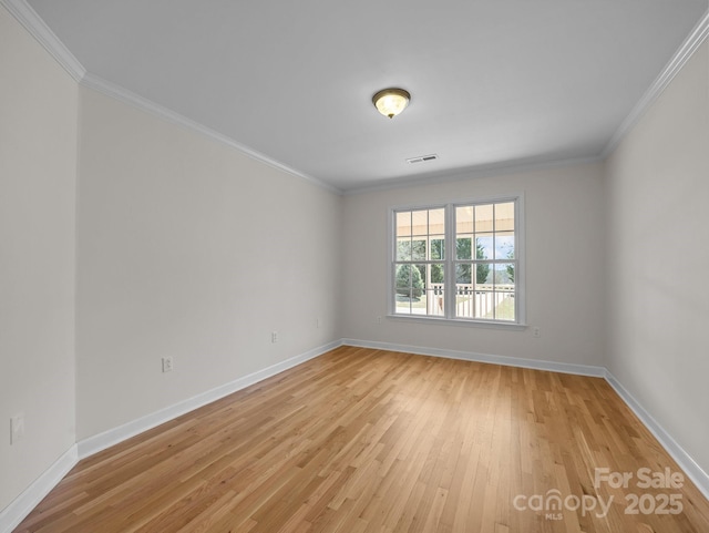 empty room featuring visible vents, light wood-style flooring, baseboards, and ornamental molding