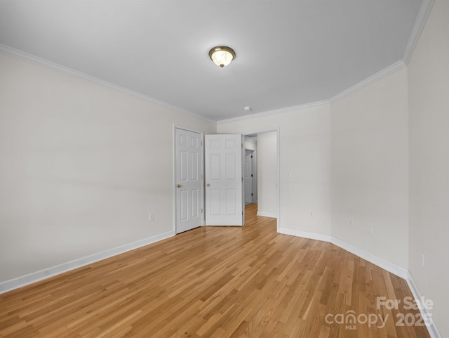 spare room with light wood-style flooring, crown molding, and baseboards