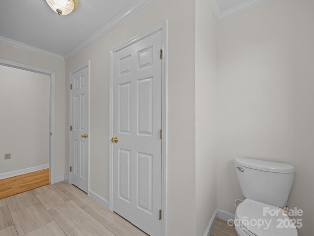 bathroom featuring baseboards, toilet, and ornamental molding