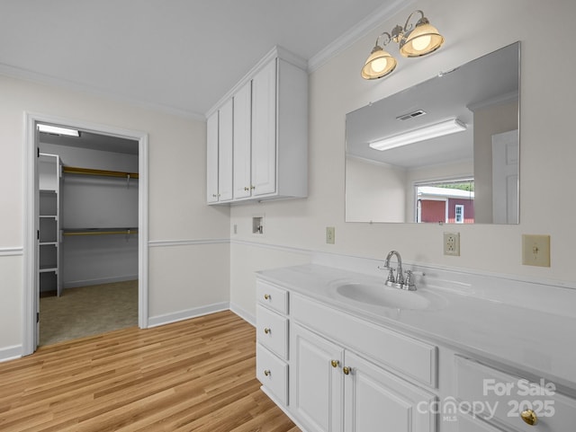 bathroom with visible vents, baseboards, ornamental molding, wood finished floors, and vanity