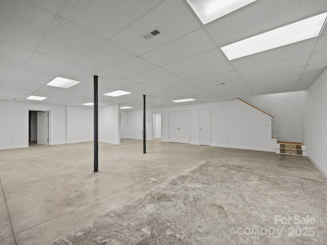 basement with visible vents, baseboards, and a drop ceiling