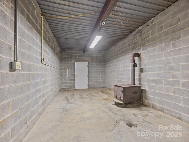 basement with a wood stove and concrete block wall