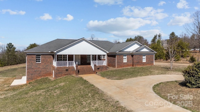 ranch-style house with brick siding, a porch, driveway, and a front yard