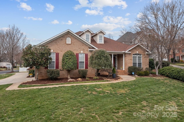 view of front facade featuring brick siding, driveway, and a front yard