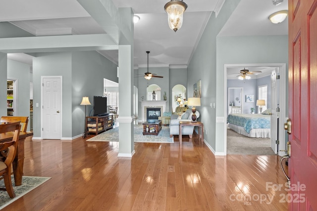 entryway with a glass covered fireplace, crown molding, ceiling fan, and wood-type flooring