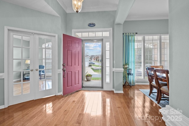 entrance foyer featuring a wealth of natural light, french doors, crown molding, and hardwood / wood-style flooring