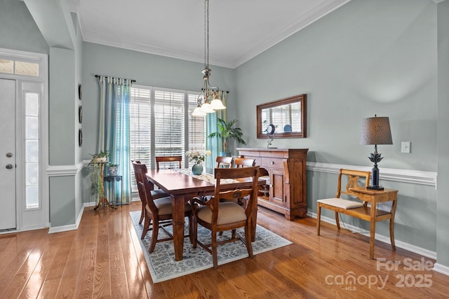 dining area featuring an inviting chandelier, crown molding, light wood-style floors, and baseboards