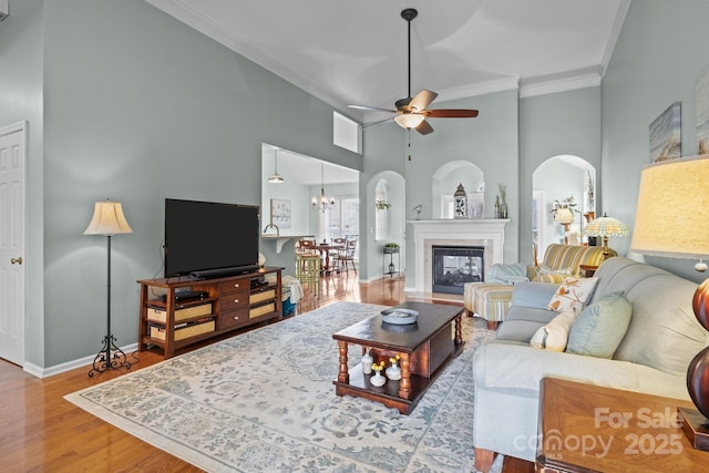 living room featuring wood finished floors, arched walkways, ceiling fan, and crown molding