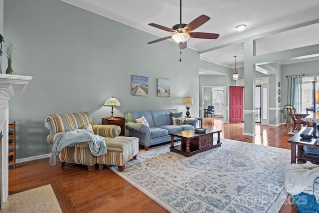 living room featuring ornamental molding, wood finished floors, baseboards, and ceiling fan