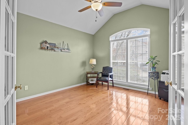 living area featuring a wealth of natural light, lofted ceiling, a ceiling fan, and wood finished floors