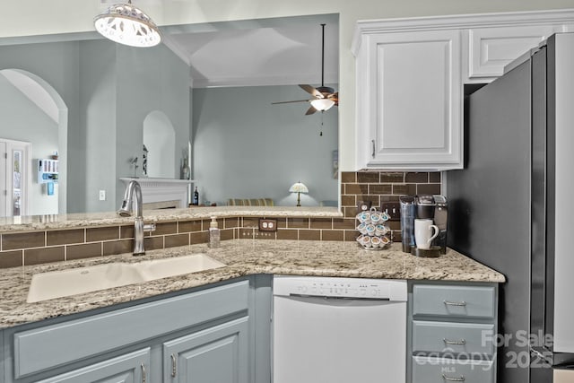 kitchen featuring white dishwasher, freestanding refrigerator, ceiling fan, decorative backsplash, and a sink