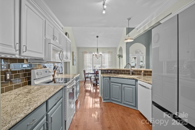 kitchen featuring white appliances, gray cabinets, a sink, light wood-style floors, and tasteful backsplash