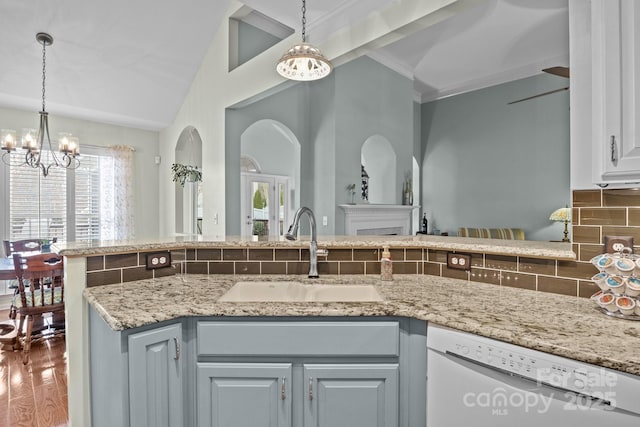 kitchen with tasteful backsplash, a chandelier, dishwasher, pendant lighting, and a sink