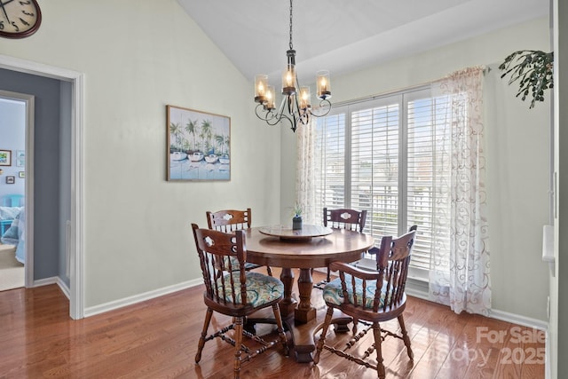 dining room with a notable chandelier, baseboards, lofted ceiling, and wood finished floors